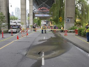 A sinkhole appeared at the entranceway to Granville Island on Saturday, June 3, 2017, after a sewer pipe beneath the street burst. Vehicle traffic was limited as city crews worked to repair the pipe and restore the road.