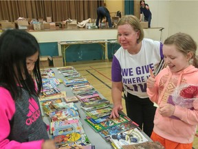 Volunteer Margaret Fiddes, a retired Telus employee, helps Norquay elementary school students Ella Tsang (left) and Tania Bray choose books in the east Vancouver school’s annual book exchange.