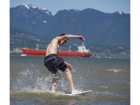A skim boarder takes advantage of the summer sunshine to play at Spanish Banks, Vancouver.