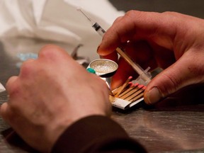 FILE PHOTO A man prepares heroin he bought on the street to be injected at the Insite safe injection clinic in Vancouver, B.C., on Wednesday May 11, 2011.