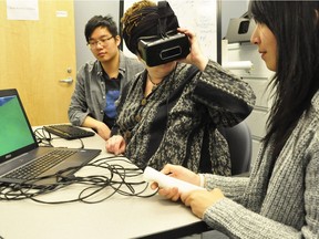 SFU SIAT students Henry Lo and Janice Ng work with professor Diane Gromala on their virtual reality game Farmooo, designed to help cancer patients manage their treatment pain.