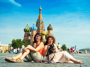 Tourists sitting on Red Square in Moscow, Russia. Saint Basil's Cathedral in the background.