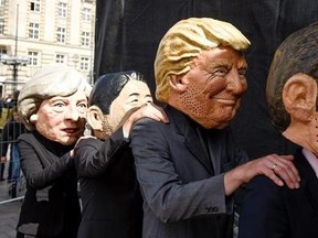 Demonstrators against the G20 Summit stand on stage wearing masks depicting from left : British Prime Minister Theresa May, Japan&#039;s Prime Minister Shinzo Abe, US President Donald Trump and French President Emmanuel Macron, in Hamburg, Germany, Sunday, July 2, 2017. (Axel Heimken/dpa via AP)