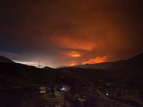 A wildfire burns on a mountain in the distance east of Cache Creek behind a trailer park that was almost completely destroyed by wildfire, in Boston Flats, B.C., in the early morning hours of July 10, 2017. Federal officials visiting wildfire-affected communities in British Columbia are expected to give an update today on the state of the response. Members of a federal ad hoc committee leading the government&#039;s fire response, including Public Safety Minister Ralph Goodale and Defence Minister Har