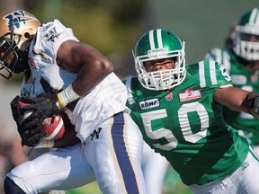 Winnipeg Blue Bombers wide receiver Cory Watson breaks a tackle from Saskatchewan Roughriders linebacker Jerrell Freeman in the third quarter of CFL football action at Mosaic Stadium on Sunday, Sept. 4, 2011 in Regina. Freeman has always been on the ball on the football field, but his quick thinking Sunday saved a man&#039;s life. THE CANADIAN PRESS/Liam Richards