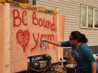 Marie-Lise Landry, 34, spray-paints a message on an 18-foot trailer filled with supplies for B.C. firefighters, in Fort McMurray, Alta. on Saturday, July 8, 2017. The trailer, hauling tonnes of supplies and 700 litres of fuel, left Sunday morning for Kamloops, B.C.