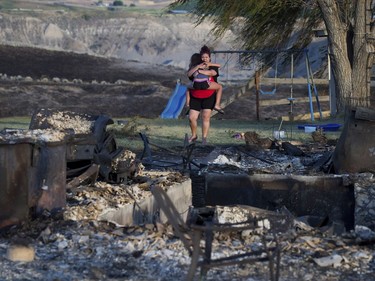Kelsey Thorne holds her daughter Nevaeh Porter, 8, as they both cry while viewing the remains of their home where they lived with her parents that was destroyed by a wildfire on the Ashcroft First Nation, near Ashcroft, British Columbia, late Sunday, July 9, 2017.