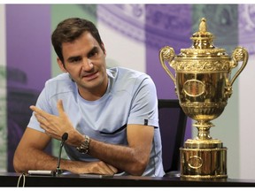 Tennis star Roger Federer speaks next to the men's singles trophy he won earlier this month at Wimbledon, England.