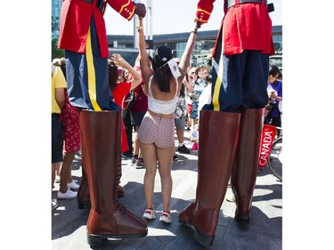Stilt walkers dressed as Mounties pose for a photo with a woman at the Canada Day celebrations at Canada Place, Vancouver, July 01 2017.