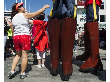 A woman reaches for a stilt walker dressed as a Mountiesin the crowd at the Canada Day celebrations at Canada Place, Vancouver, July 01 2017.