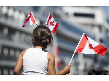 A young girl carries flags at the Canada Day celebrations at Canada Place, Vancouver, July 01 2017.