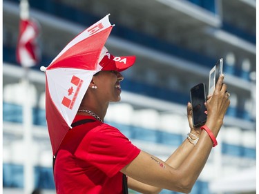 A woman dressed in red and white takes a photo of friends at the Canada Day celebrations at Canada Place, Vancouver, July 01 2017.