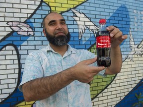 Zahid Mahmood holds a bottle of Coca-Cola bearing the tagline "Missing You" outside his store Hasty Market 3150 Main St Vancouver, July 26 2017.