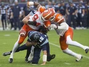 Toronto Argonauts quarterback Ricky Ray is sacked by B.C. Lions' DeQuin Evans, left, and Bryant Turner Jr. during first half CFL football action in Toronto on Friday, June 30.