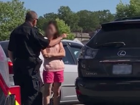 This is a screengrab from a Facebook video that shows a Vancouver police officer lecturing a mother about leaving kids inside a locked car on a hot day.