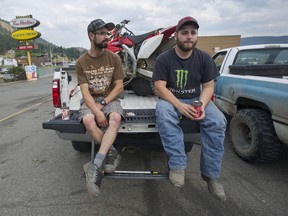 Laird Tutte (left) and Geremy Murphy drink coffee on the tailgate of a pick-up truck in Williams Lake, BC Wednesday, July 12, 2017.