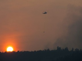 Williams Lake, BC: July 12, 2017 -- As the sun sets a helicopter prepares to dump water on a blaze near Williams Lake, BC Wednesday, July 12, 2017. The residents of Williams Lake are on alert for possible evacuation due to raging wildfires in the region.  (Photo by Jason Payne/ PNG) (For story by Gord Hoekstra) ORG XMIT: bcwildfire [PNG Merlin Archive]

VANCOUVER OUT
Jason Payne, PNG