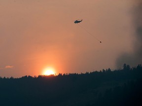 As the sun sets on Wednesday, a helicopter prepares to dump water on a blaze near Williams Lake.