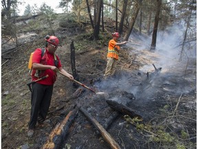 Firefighters Dave Cady (with hose) and Scott Williams (shovel), from Borland Creek Logging, put out a hot spot Friday above the Coyote Rock Golf Course on Williams Lake Indian Band land south of Williams Lake.