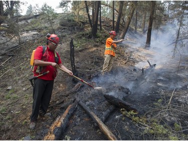 Firefighters Dave Cady (with hose) and Scott Williams (shovel), from Borland Creek Logging, put out a hot spot above the Coyote Rock golf course on Williams Lake Indian band land south of Williams Lake Friday, July 14, 2017.