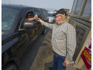 Many businesses in Williams Lake are closed as the threat from wildfires have left many businesses without staff. Pictured is Vic Sharma, owner of the family-operated Tim Hortons on Highway 97, handing out free water to customers in his restaurant's drive-thru.