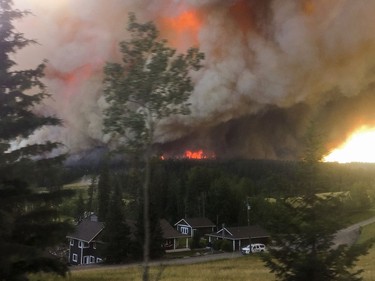 A large wildfire burns on the ridge behind the Braaten Home in 153 Mile House.