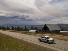 An RCMP officer drives north on Highway 97S near Alexandria, B.C., while a large plume of smoke from the forest fires burning around Williams Lake can be seen on the horizon, July, 16, 2017.
