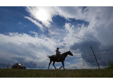 Bonnie Martin rides her horse on Highway 97S en route to Kersley with her boyfriend driving in the car behind while evacuating her home town of Alexandria, BC, July, 16, 2017. Martin does not know anyone with a trailer and riding is her only way out of town with her horse.