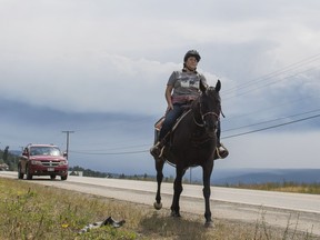 Bonnie Martin rides her horse on Highway 97S en route to Kersley, with her boyfriend driving in the car behind, while evacuating her home town of Alexandria. Martin does not know anyone with a trailer and riding is her only way out of town with her horse.