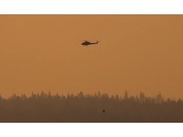 A helicopter with a water bucket works on the Soda Creek Fire near Alexandria, BC, July, 16, 2017.