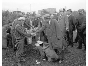 Rev. Andrew Roddan (standing to the right of the men handing out food, looking at camera) helps distribute food at the hobo jungle at the Vancouver city dump on the False Creek Flats in 1931. Roddan was a social reformer who wrote a book about Vancouver's hobos, God in the Jungles.