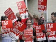 Demonstrators stand together as they wait for a Republican response to a new city income tax on the wealthy that was approved earlier by the Seattle City Council Monday, July 10, 2017, in Seattle. Seattle's wealthiest will become the only Washington state residents to pay an income tax under legislation unanimously approved by the City Council, a measure designed as much to raise revenue as to open a broader discussion about whether the wealthy pay their fair share.