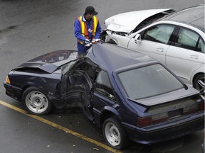 A worker examines damaged vehicle at an ICBC lot at the south end of the Queensborough Bridge in Richmond.