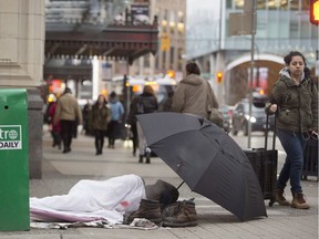 Pedestrians walk past a person sleeping on the street in downtown Vancouver, B.C., Monday, Jan. 30, 2017.