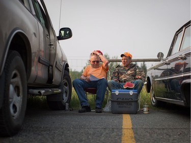 Garth Lee, left, and his son Floyd Lee, both evacuated from their homes in 108 Mile Ranch, sit in the parking lot outside a curling club being used as an evacuation centre in 100 Mile House, B.C., on Saturday July 8, 2017.