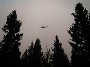 A helicopter carrying a bucket battles the Gustafsen wildfire near 100 Mile House, B.C., on Saturday July 8, 2017.