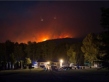 A wildfire burns on a mountain behind a home in Cache Creek, B.C., in the early morning hours of Saturday July 8, 2017. More than 3,000 residents have been evacuated from their homes in central British Columbia.