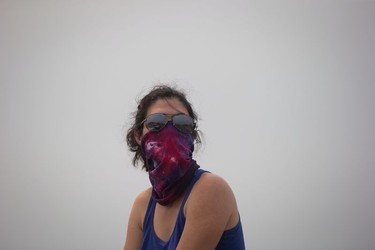Luana Avila wears a bandana over her face because of smoke and ash in the air from wildfires as she waits for her children at a gas station in Little Fort, B.C., on Saturday July 8, 2017. Avila and her husband, from Vancouver, were waiting for his parents to drop off their kids who were staying with them in 100 Mile House.