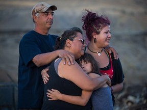 Randy Thorne, left, his wife Angie Thorne, second left, their daughter Kelsey Thorne, and granddaughter Nevaeh Porter, 8, comfort one another after being overcome with emotion as they view the remains of their home that was destroyed by wildfire on the Ashcroft First Nation, near Ashcroft.