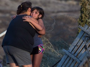 Nevaeh Porter, 8, is comforted by her grandmother Angie Thorne as they view the remains of their home that was destroyed by wildfire on the Ashcroft First Nation, near Ashcroft, B.C., late Sunday July 9, 2017.