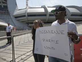 MONTREAL, QUE.: AUGUST 2, 2017 --Naomi Jolicoeur and Max LeGrande stand outside Olympic stadium with sign, to welcome Haitian refugees arriving by bus at the facility on Wednesday August 2, 2017. (Pierre Obendrauf / MONTREAL GAZETTE) ORG XMIT: 59104 - 7351