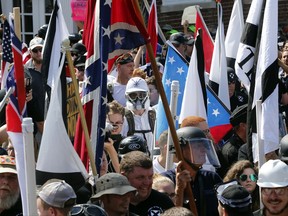 FILE - In this Saturday, Aug. 12, 2017, file photo, white nationalist demonstrators walk into the entrance of Lee Park surrounded by counter demonstrators in Charlottesville, Va. People are using social media to identify and shame white nationalists who attended this past weekends gathering in Charlottesville. At least one person has reportedly been fired as a result, showing that the power of angry online mobs can go both ways.