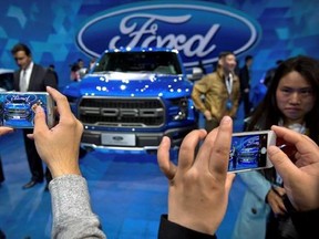 In this April 23, 2016, photo, attendees take smartphone photos at a promotional event for Ford Motor Company ahead of the Auto China car show in Beijing. Ford Motor Co. announced an agreement Tuesday, Aug. 22, 2017 with a Chinese partner to look into forming a joint venture to develop and manufacture electric cars in China. (AP Photo/Mark Schiefelbein)