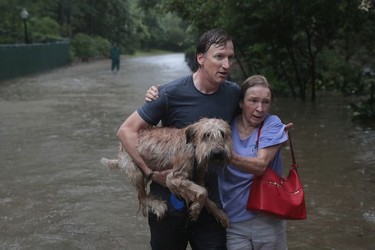 Andrew White (L) helps a neighbour down a street after rescuing her from her home in his boat in the upscale River Oaks neighbourhood after it was inundated with flooding from Hurricane Harvey on August 27, 2017 in Houston, Texas.