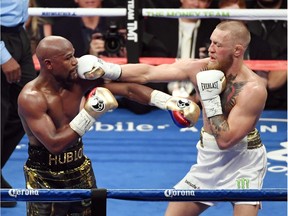 Floyd Mayweather (L) and Jr. Conor McGregor battle in the sixth round of their super welterweight boxing match Saturday in Las Vegas. Mayweather won by 10th-round TKO.