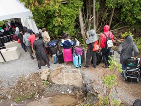 A long line of asylum seekers wait to illegally cross the Quebec/U.S border.