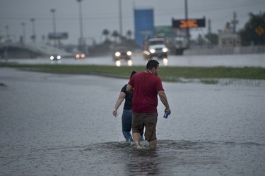 People walk through flooded streets during the aftermath of Hurricane Harvey August 27, 2017 in Houston, Texas. Hurricane Harvey left a trail of devastation Saturday after the most powerful storm to hit the US mainland in over a decade slammed into Texas, destroying homes, severing power supplies and forcing tens of thousands of residents to flee.