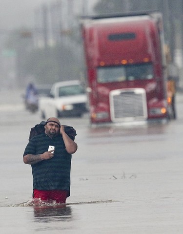 A man carries his belonging as he walks through the flooded waters on Telephone Rd. in Houston on August 27, 2017 as the US fourth city city battles with tropical storm Harvey and resulting floods.