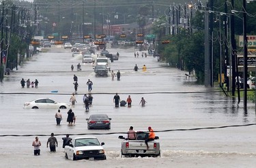 People walk through the flooded waters of Telephone Rd. in Houston on August 27, 2017 as the US fourth city city battles with tropical storm Harvey and resulting floods.