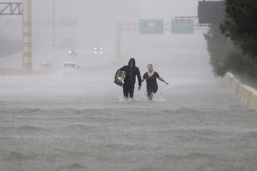 Two people walk down a flooded section of Interstate 610 in floodwaters from Tropical Storm Harvey on Sunday, Aug. 27, 2017, in Houston, Texas.